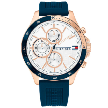 Oryginalny zegarek męski marki Tommy Hilfiger na niebieskim, silikonowym pasku. Miedziane, fluorescencyjne wskazówki i miedziane indeksy na białej tarczy z chronografami (dni tygodnia, miesiąca i 24h). Czarno-miedziany sekundnik. Miedziana koperta zegarka o średnicy 46 mm.